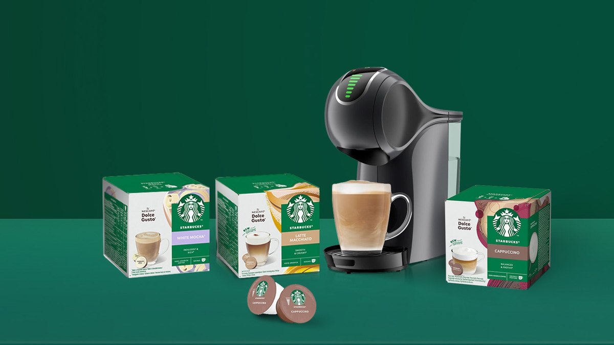 Dozen Starbucks Dolce Gusto-cups naast een Nescafé Dolce Gusto-machine met een kop cappuccino
